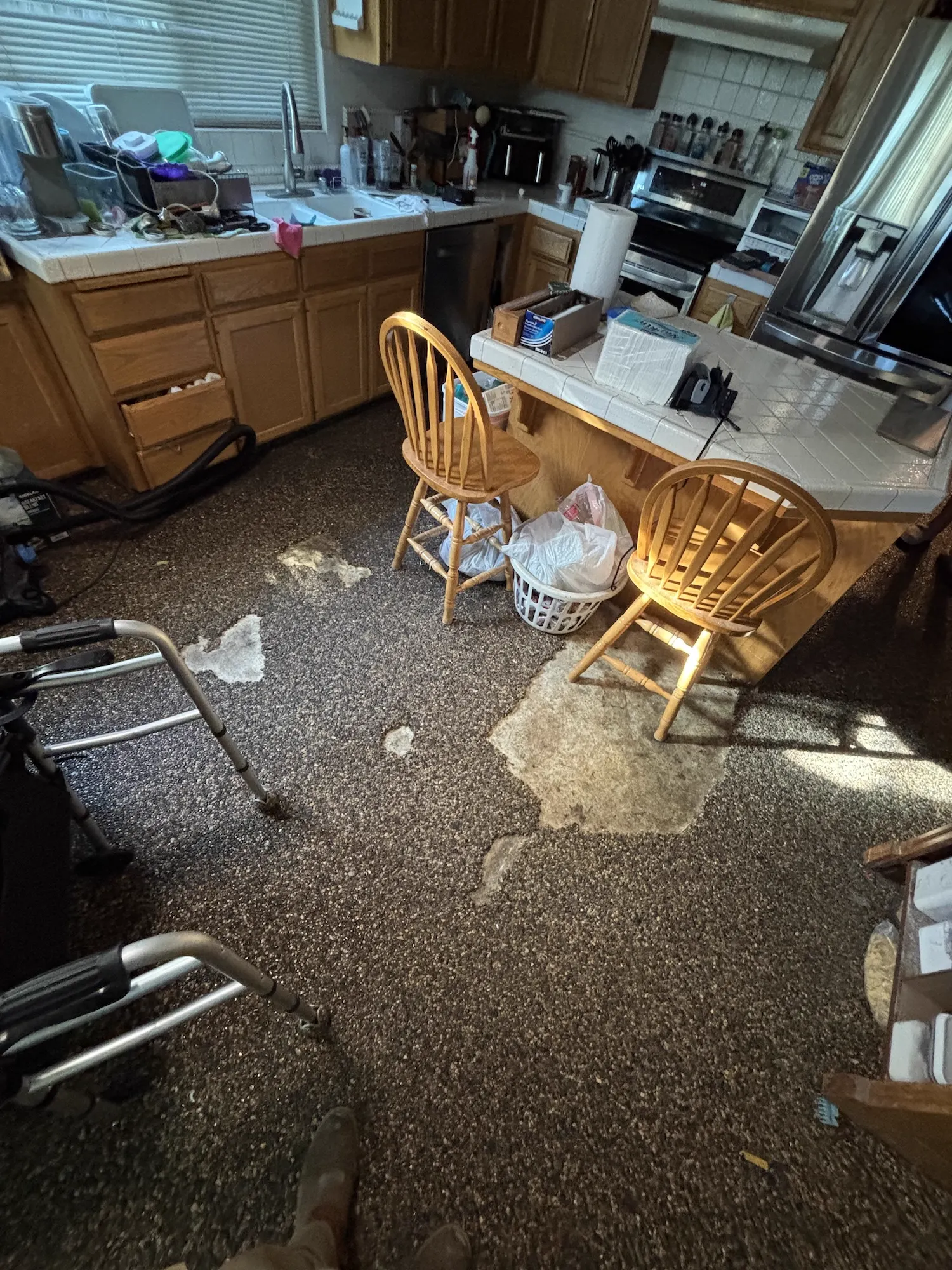Before: Kitchen floor replacement: damaged carpet torn out and replaced with wide-plank wood-look flooring throughout the kitchen and dining area.
